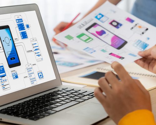 Panorama banner of startup UX developer or company employee design user interface or UI prototype for mobile application or website software with software display on laptop monitor in office. Synergic